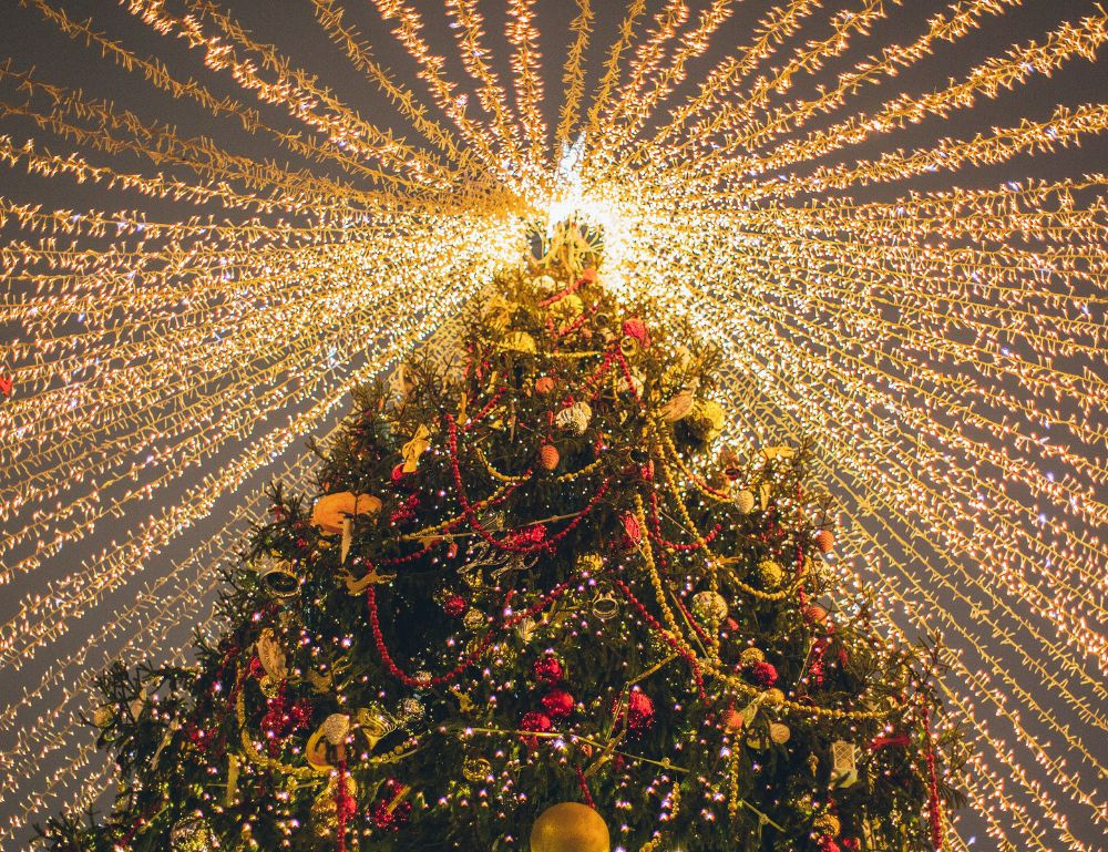 Looking up at a big tall christmas tree with lots of lights and decorations